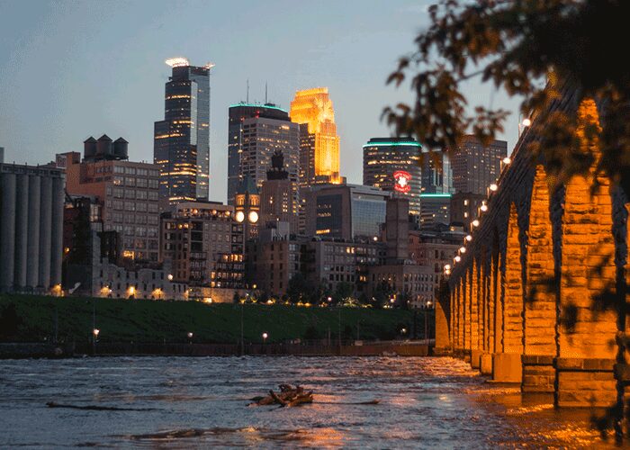 Minneapolis skyline at dusk beside the Stone Arch Bridge over the Mississippi